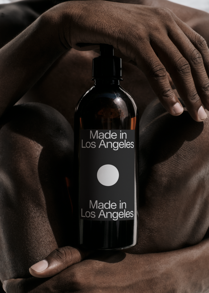 Product packaging mockup featuring a person holding an elegant black dispenser bottle with "Made in Los Angeles" label, perfect for cosmetics design presentations.